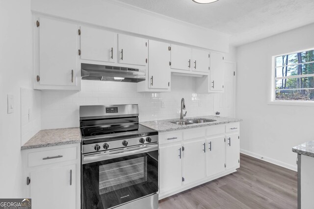 kitchen with white cabinets, sink, backsplash, light wood-type flooring, and stainless steel range with electric cooktop