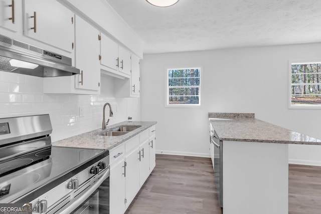 kitchen featuring stainless steel appliances, hardwood / wood-style floors, sink, decorative backsplash, and light stone countertops