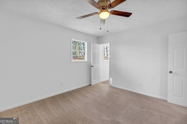 carpeted spare room with a textured ceiling and ceiling fan