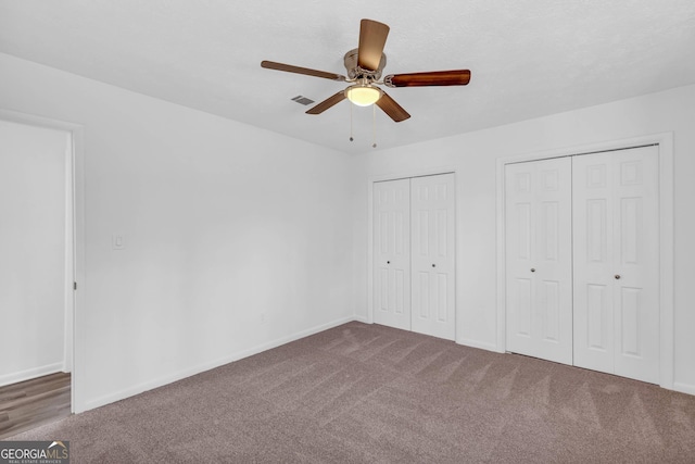 unfurnished bedroom with multiple closets, carpet floors, and ceiling fan