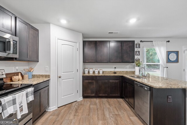 kitchen with dark brown cabinetry, stainless steel appliances, light hardwood / wood-style floors, and sink