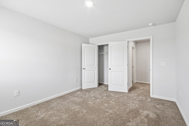 unfurnished bedroom featuring light carpet and a closet