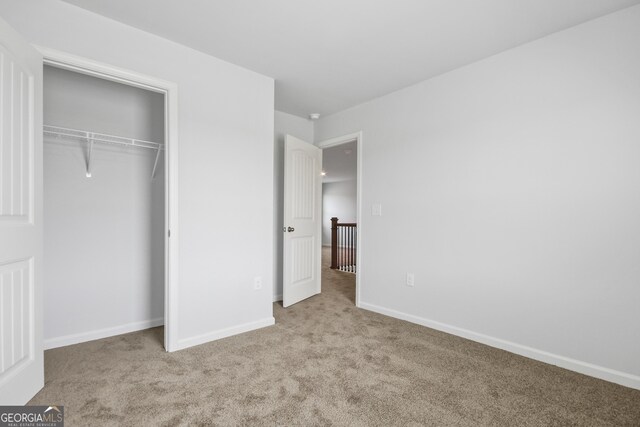 unfurnished bedroom featuring a closet and light colored carpet