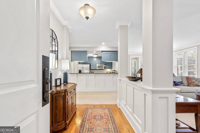 kitchen with stainless steel appliances, ornamental molding, light hardwood / wood-style floors, and kitchen peninsula