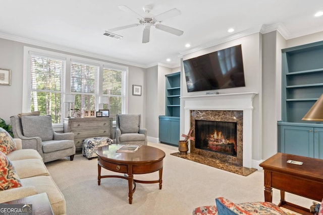 carpeted living room featuring built in shelves, a premium fireplace, and crown molding