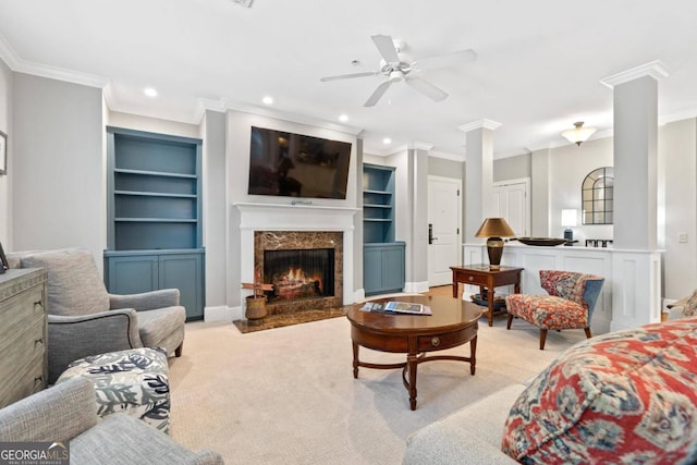 carpeted living room featuring decorative columns, crown molding, a fireplace, and built in shelves