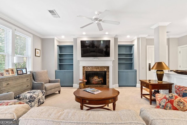 living room with ornate columns, a fireplace, ceiling fan, crown molding, and light carpet