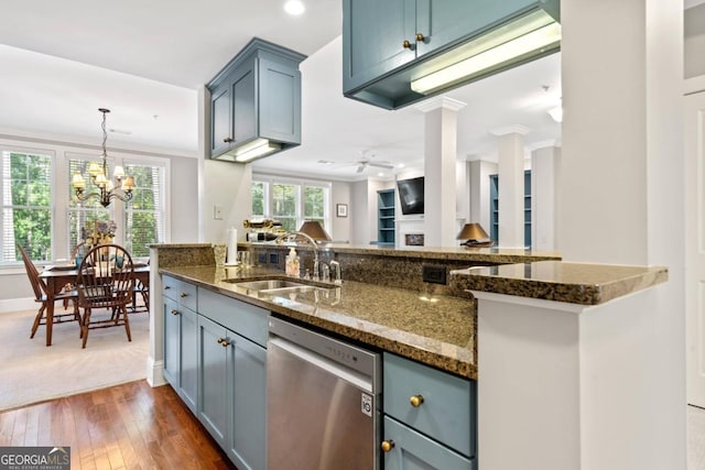 kitchen with sink, dark hardwood / wood-style floors, ceiling fan with notable chandelier, stainless steel dishwasher, and dark stone counters