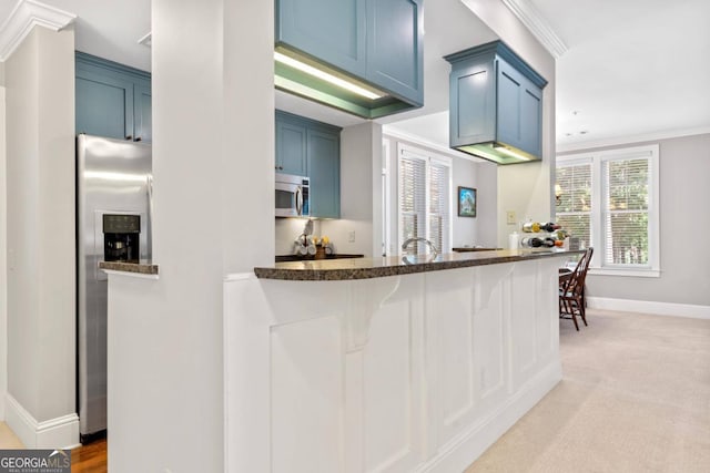 kitchen with appliances with stainless steel finishes, kitchen peninsula, and blue cabinets