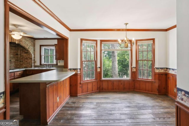 kitchen with ceiling fan with notable chandelier, hanging light fixtures, crown molding, dark hardwood / wood-style flooring, and kitchen peninsula