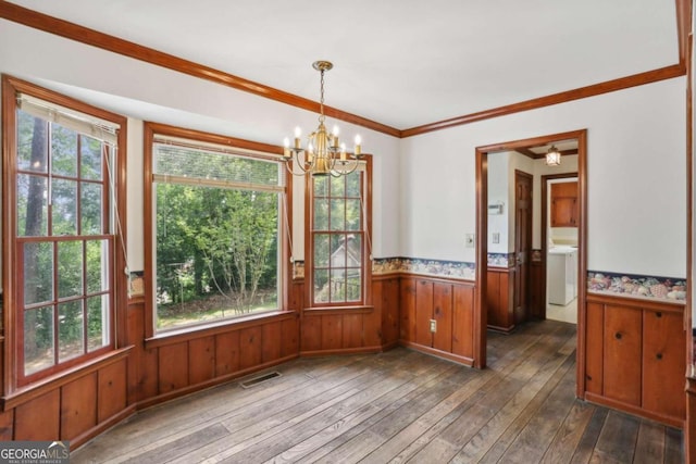 unfurnished dining area featuring a chandelier, dark hardwood / wood-style flooring, washer / clothes dryer, and crown molding