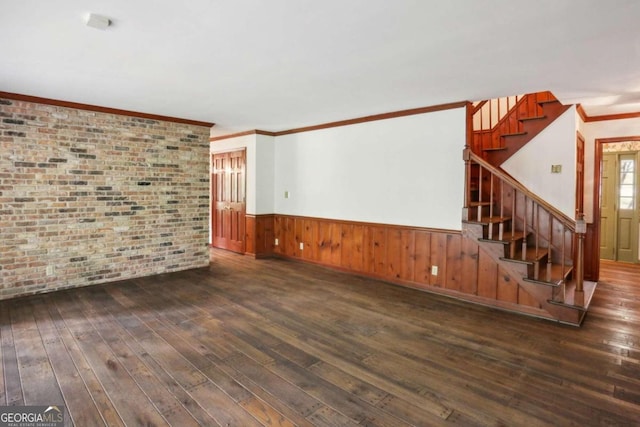 unfurnished living room with dark wood-type flooring, brick wall, and ornamental molding