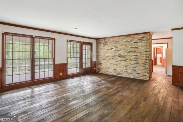 spare room featuring crown molding, dark hardwood / wood-style flooring, and brick wall