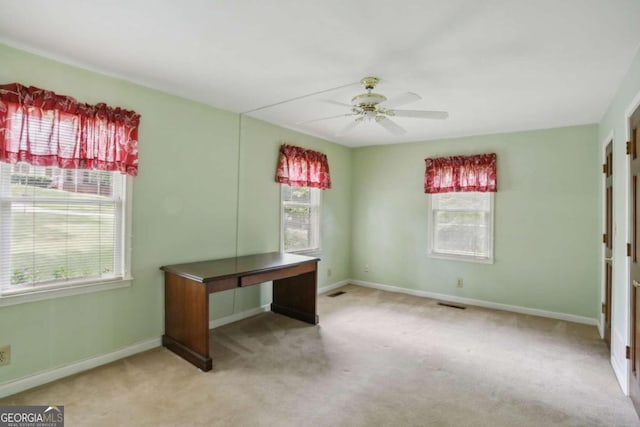 unfurnished office featuring light carpet and ceiling fan