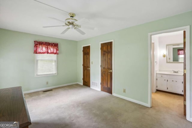 unfurnished bedroom featuring ceiling fan, sink, ensuite bathroom, and light carpet