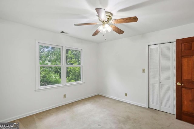 unfurnished bedroom featuring light carpet, a closet, and ceiling fan