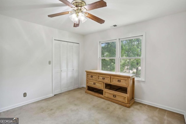 unfurnished bedroom featuring light carpet, multiple windows, a closet, and ceiling fan