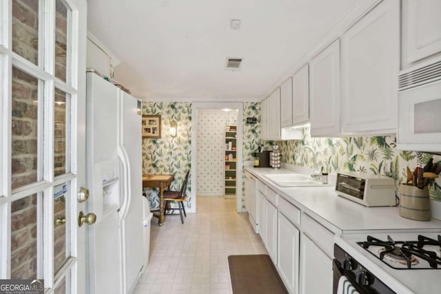 kitchen with white appliances, white cabinetry, and sink