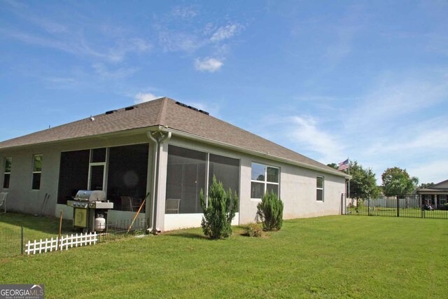 rear view of property with a sunroom and a yard