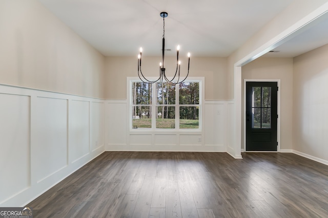 unfurnished dining area featuring a notable chandelier and dark hardwood / wood-style floors