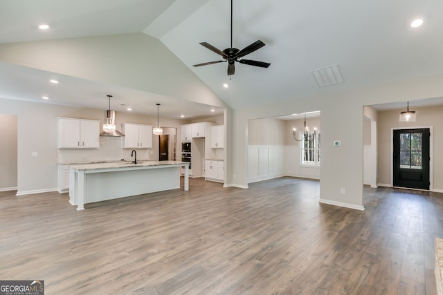 unfurnished living room featuring high vaulted ceiling, sink, ceiling fan with notable chandelier, and hardwood / wood-style floors