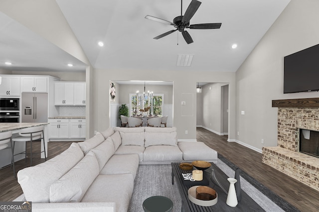 living room featuring a fireplace, vaulted ceiling, ceiling fan with notable chandelier, and dark hardwood / wood-style flooring