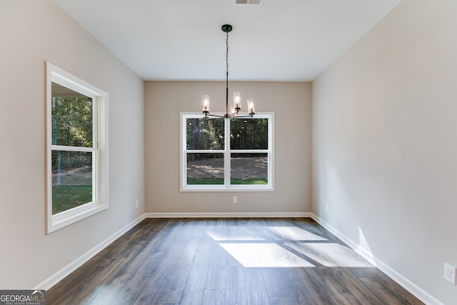 unfurnished dining area with a chandelier and dark hardwood / wood-style floors