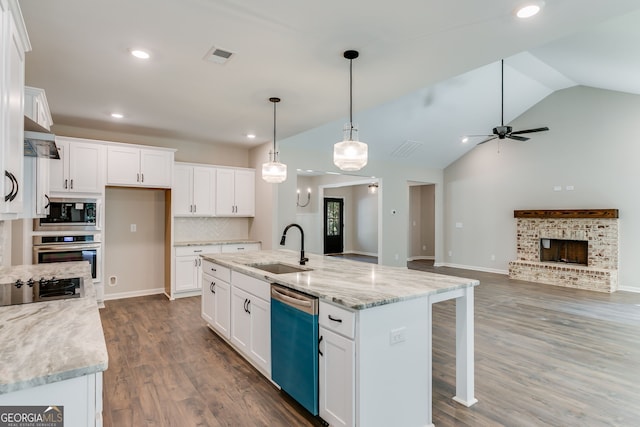 kitchen with lofted ceiling, stainless steel appliances, a center island with sink, pendant lighting, and white cabinets