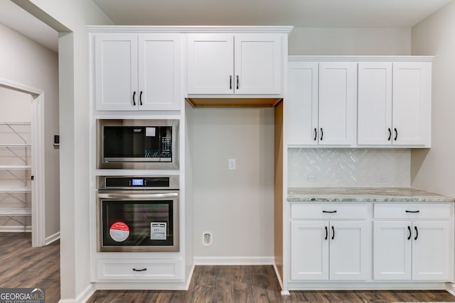 kitchen featuring light stone countertops, oven, dark hardwood / wood-style floors, and white cabinets