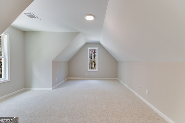 bonus room with light carpet, vaulted ceiling, and plenty of natural light