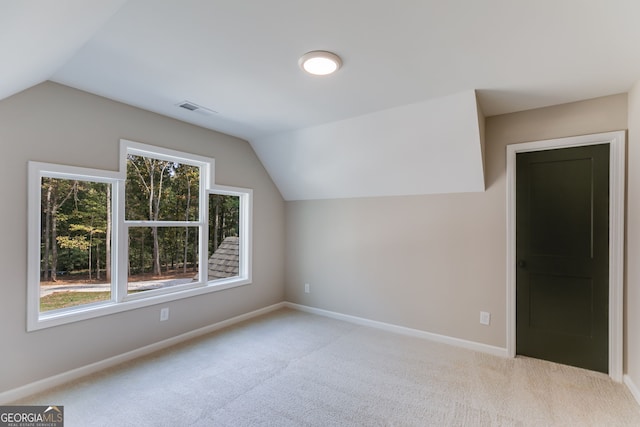 bonus room with vaulted ceiling and light carpet