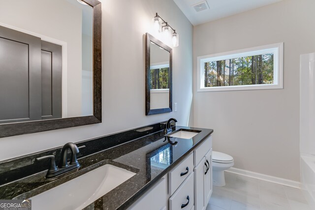 bathroom featuring vanity, a healthy amount of sunlight, toilet, and a bathtub