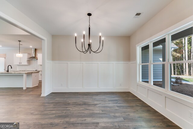 unfurnished dining area with an inviting chandelier and dark hardwood / wood-style flooring