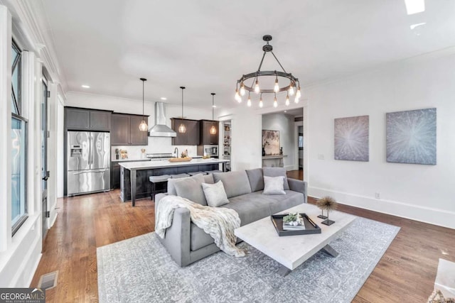 living room with a notable chandelier, hardwood / wood-style floors, and ornamental molding