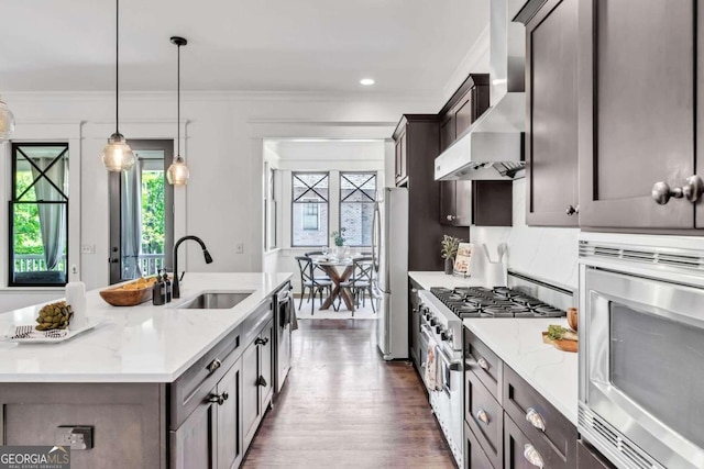 kitchen featuring appliances with stainless steel finishes, decorative light fixtures, dark hardwood / wood-style floors, light stone countertops, and wall chimney exhaust hood