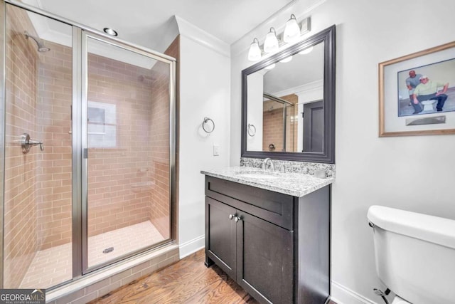 bathroom featuring crown molding, a shower with shower door, toilet, vanity, and hardwood / wood-style flooring