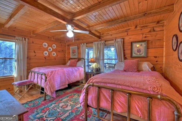 bedroom featuring beamed ceiling, ceiling fan, wooden walls, and wooden ceiling