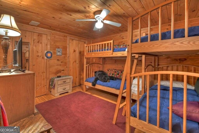 bedroom with ceiling fan, wood ceiling, wooden walls, and wood-type flooring