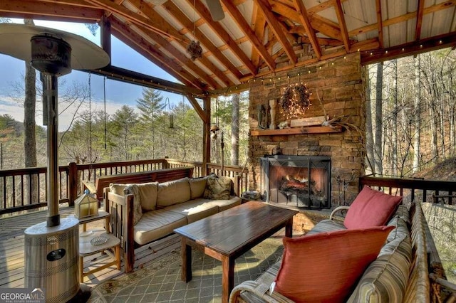 wooden terrace with an outdoor living space with a fireplace