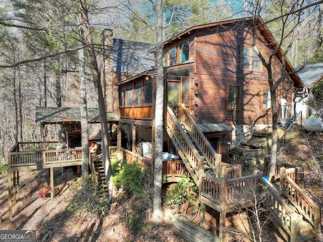 rear view of property featuring a wooden deck and a sunroom