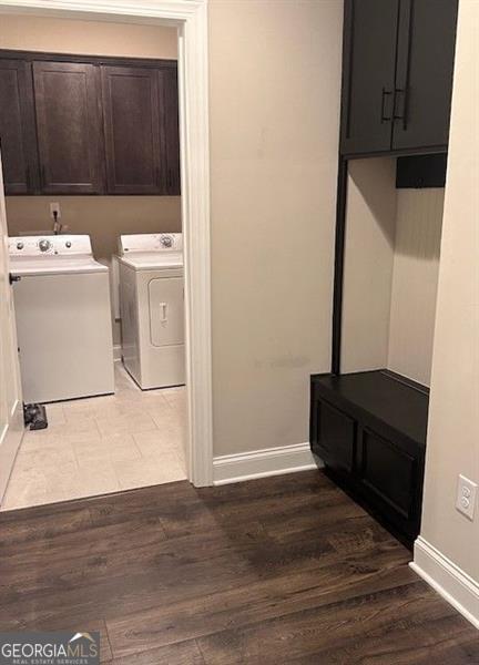 washroom with hardwood / wood-style flooring, washer and clothes dryer, and cabinets