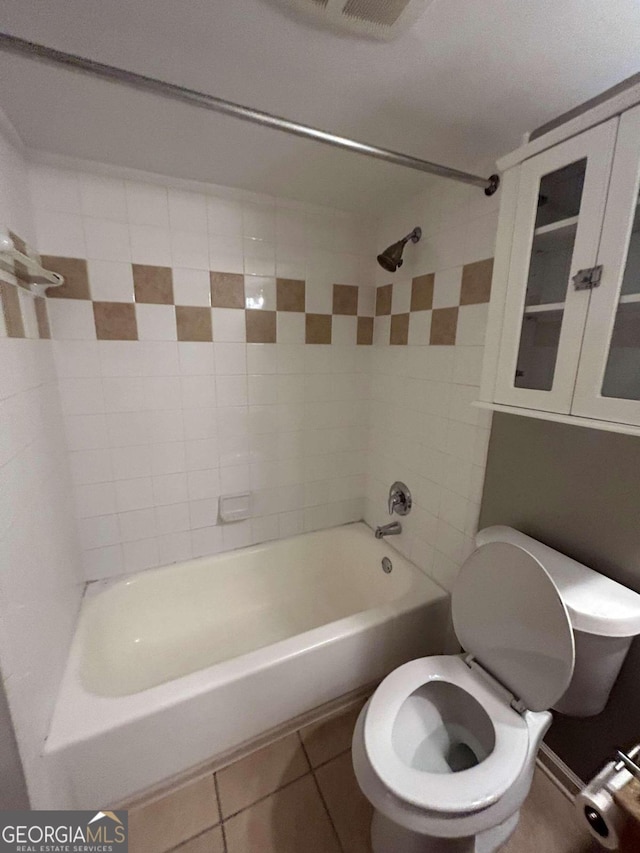 bathroom with tiled shower / bath combo, toilet, and tile patterned floors