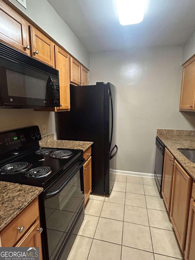 kitchen with sink, dark stone counters, black appliances, and light tile patterned floors