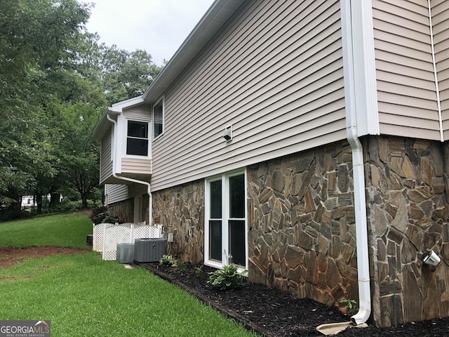 view of side of property featuring a lawn and central AC