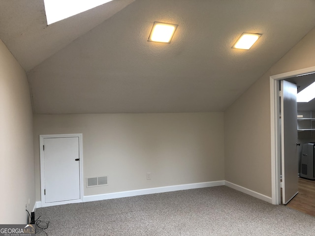 bonus room featuring carpet, lofted ceiling, and a textured ceiling