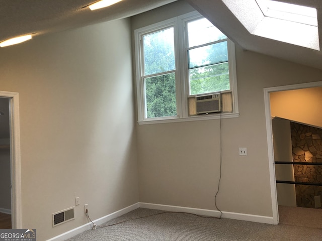 additional living space with cooling unit, lofted ceiling with skylight, and carpet floors