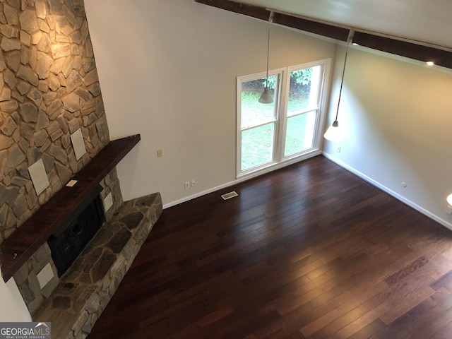 unfurnished living room with a fireplace, dark wood-type flooring, and lofted ceiling with beams