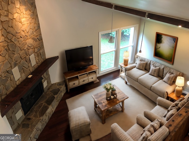 living room with a stone fireplace, dark wood-type flooring, and lofted ceiling with beams