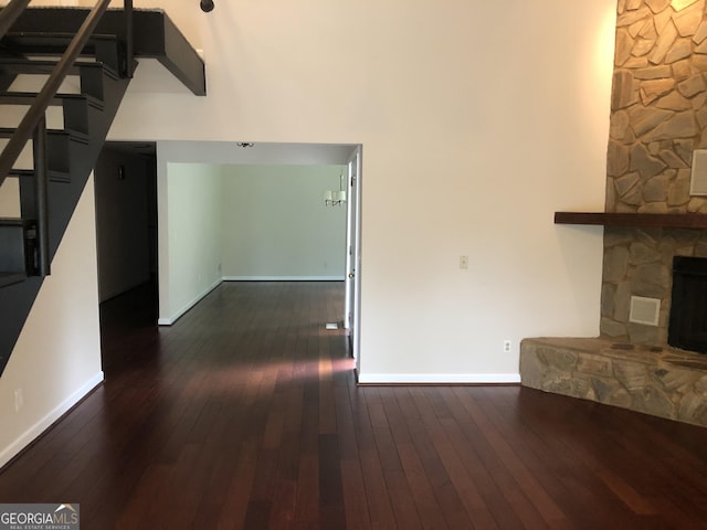 unfurnished living room with dark hardwood / wood-style flooring and a stone fireplace