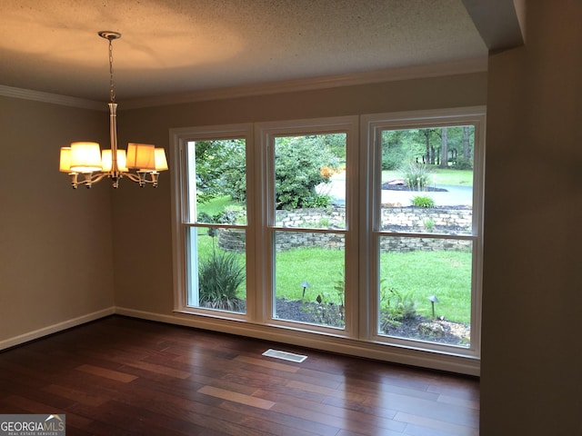 unfurnished dining area with a chandelier, ornamental molding, dark wood-type flooring, and a textured ceiling